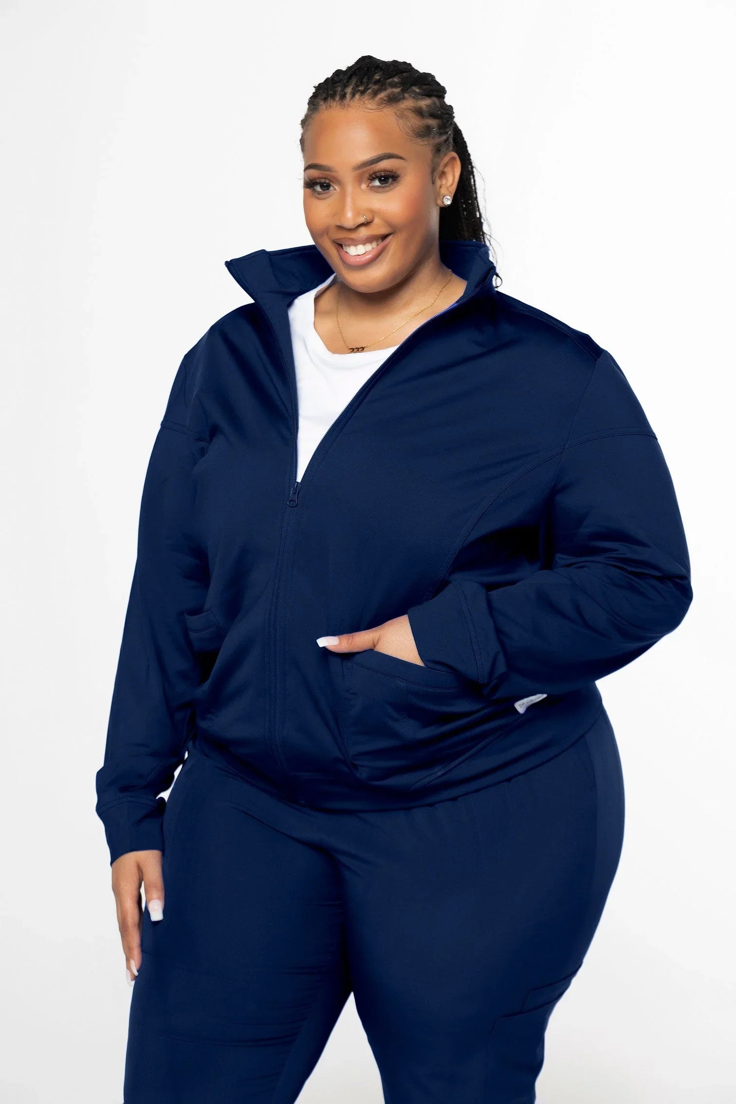 smiling woman in navy blue zip-up jacket and pants set against white background