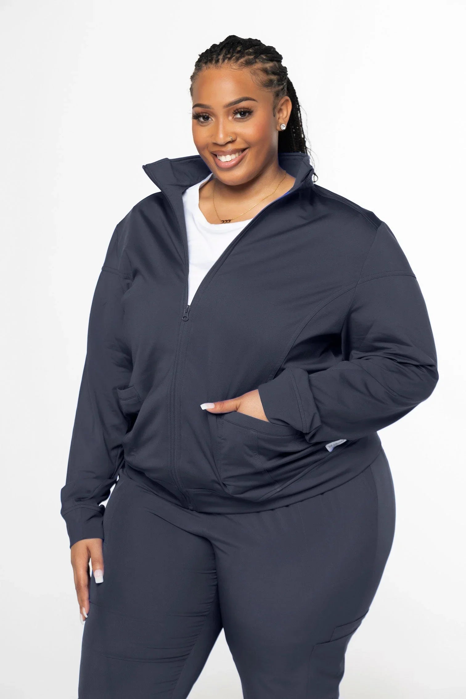 Plus size woman smiling in a navy blue zip-up jacket and matching pants with a white top