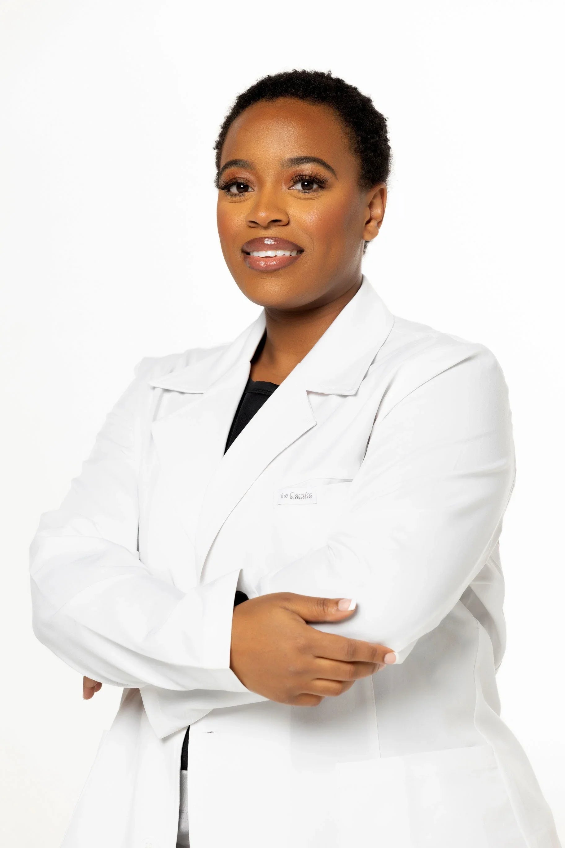 Confident Black woman in white medical lab coat with arms crossed on white background