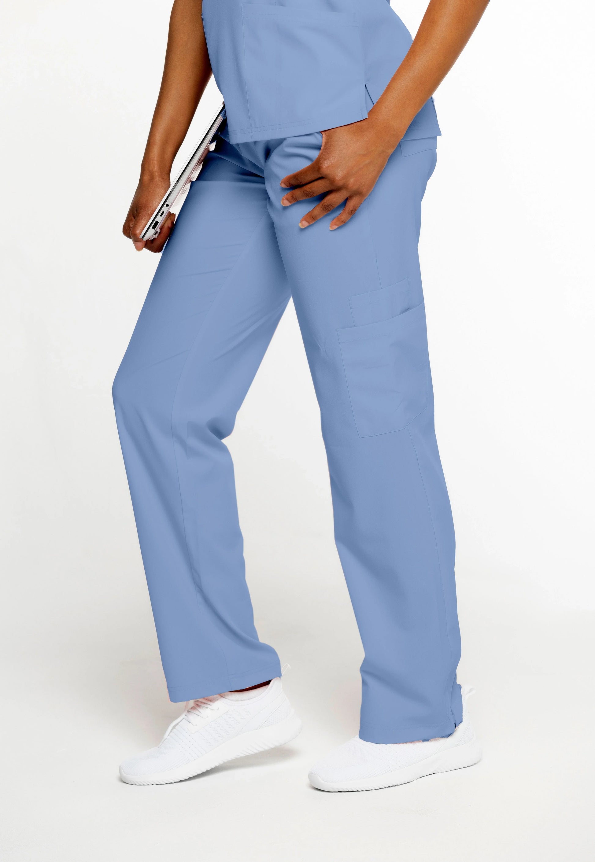 Person wearing light blue medical scrub pants with side pockets and white sneakers holding a tablet