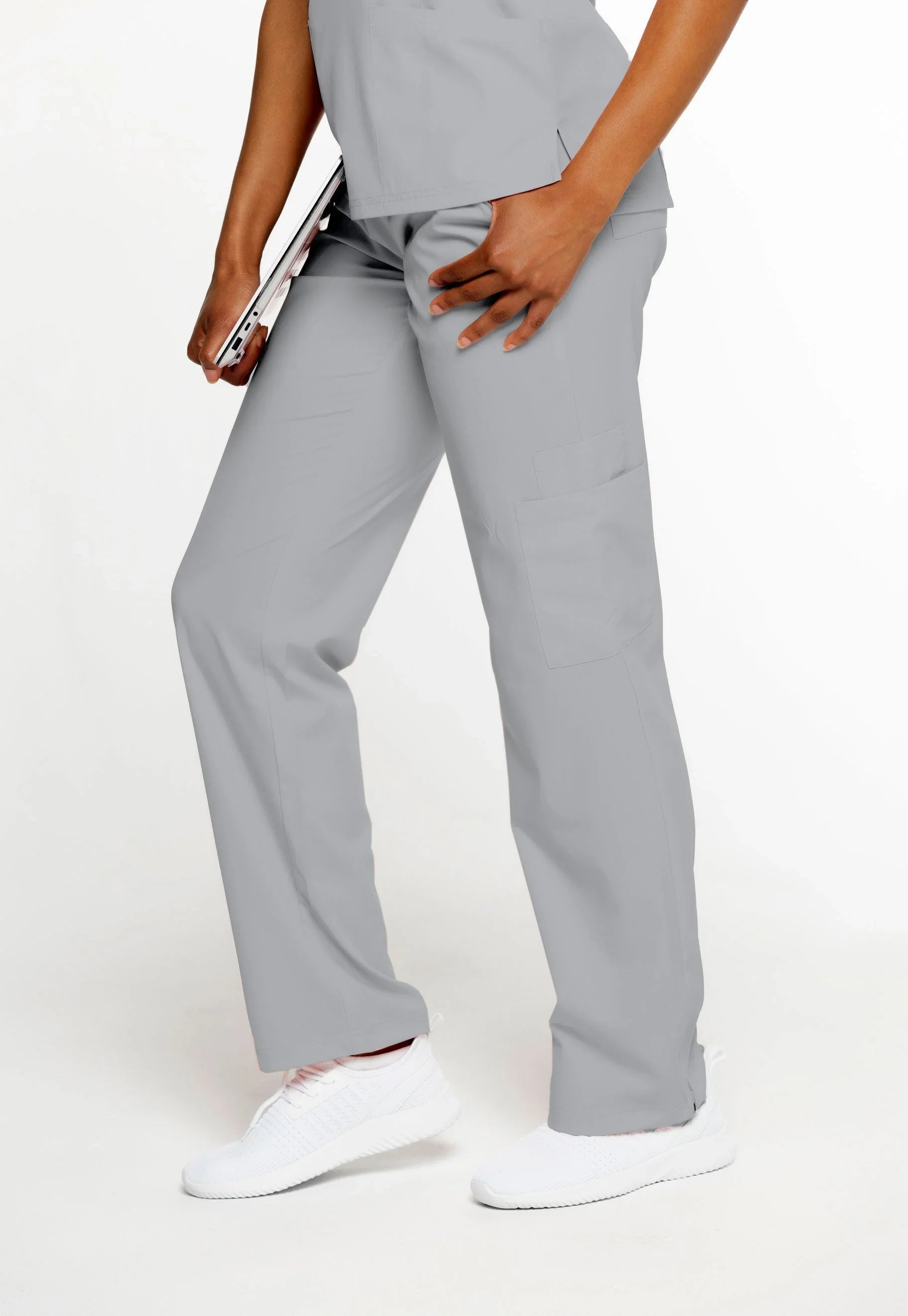 Person wearing gentle gray medical scrub pants with pockets and white sneakers holding a tablet
