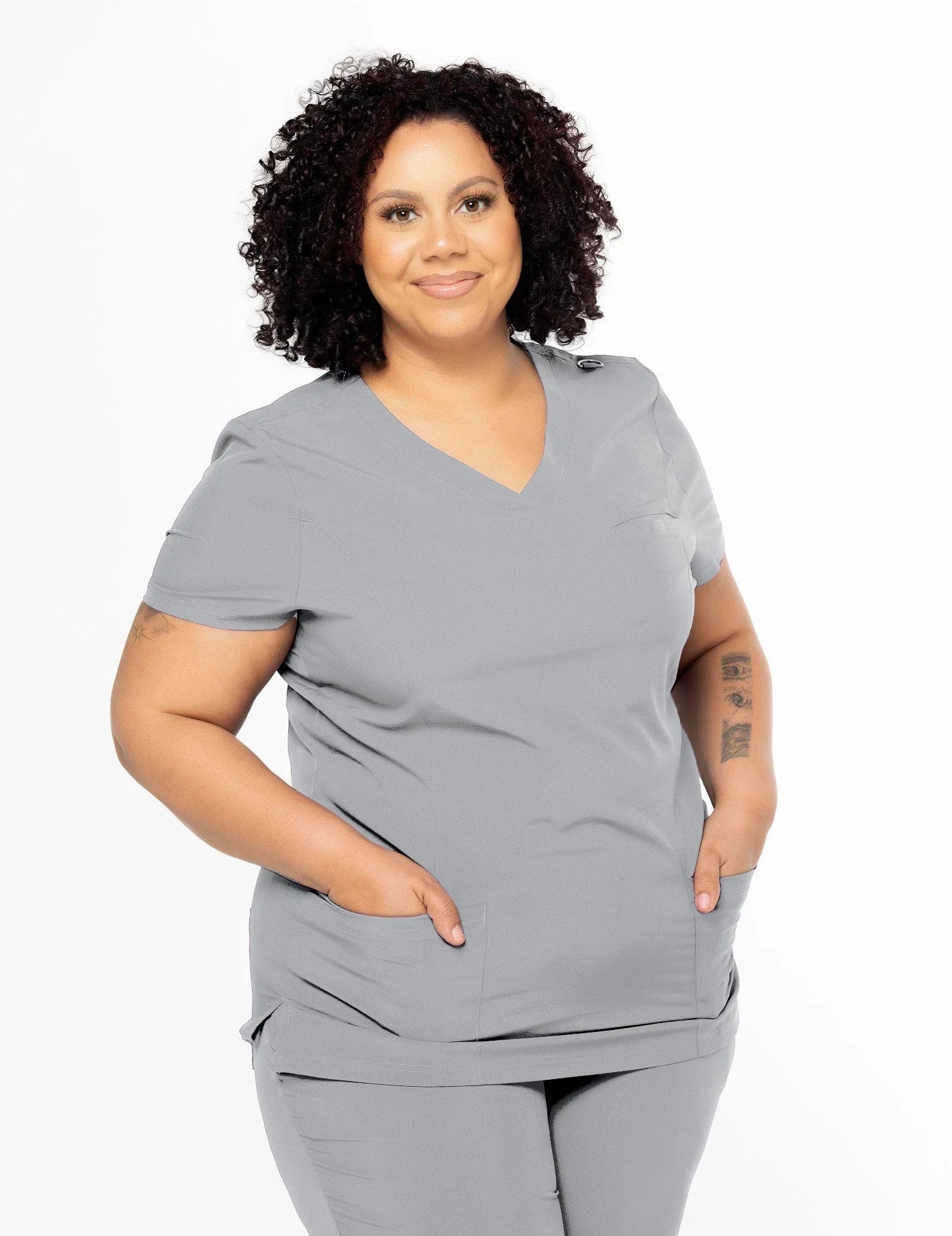 Smiling woman in gray medical scrub set with V-neck and pockets on white background
